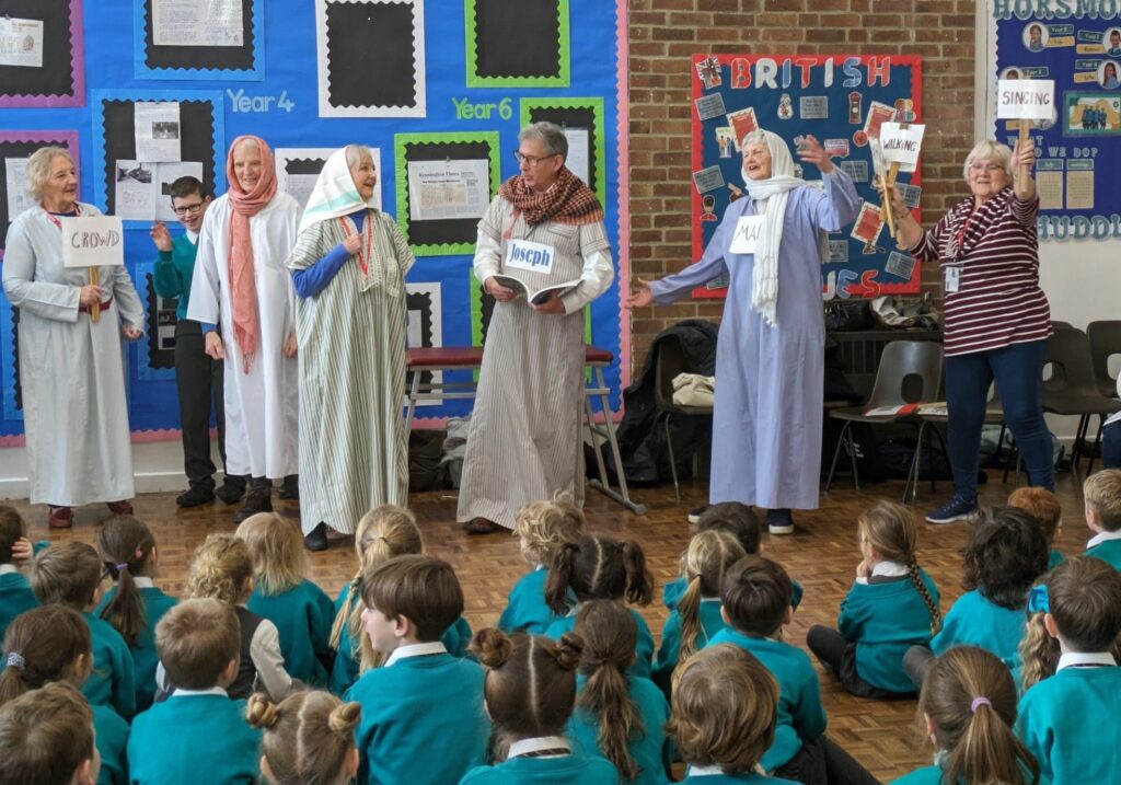 Visitors from the 'Open the Book' Team are pictured delivering a performance of the story 'Where's Jesus?' to a large group of pupils gathered in the school hall.