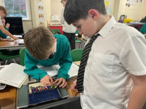 Two boys in academy uniform are seen examining a collection of medals from WWII.
