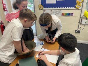 A small group of four pupils in academy uniform can be seen looking closely at some WWII memorabilia, whilst stood around a table.