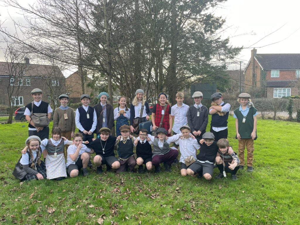 A group photo of students dressed as evacuees, outside on a grassy area.