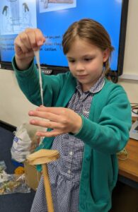 A female pupil from Year 3 is seen carding fleece in a Design & Technology class.