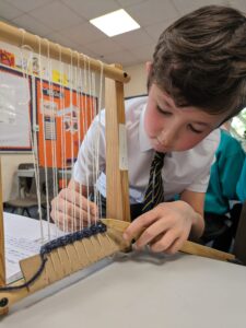 A male pupil from Year 3 is pictured creating his own loom during a Design & Technology class.
