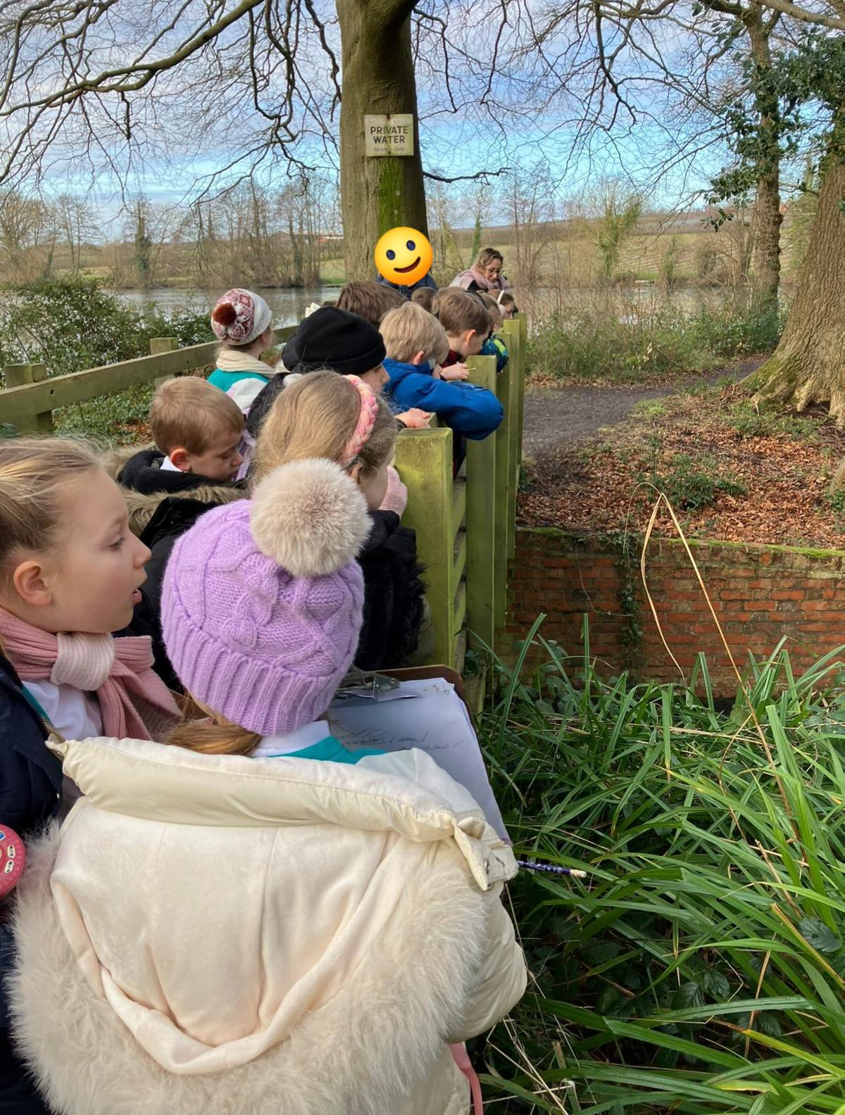 A group of students looking over a wooden bridge railing at a stream