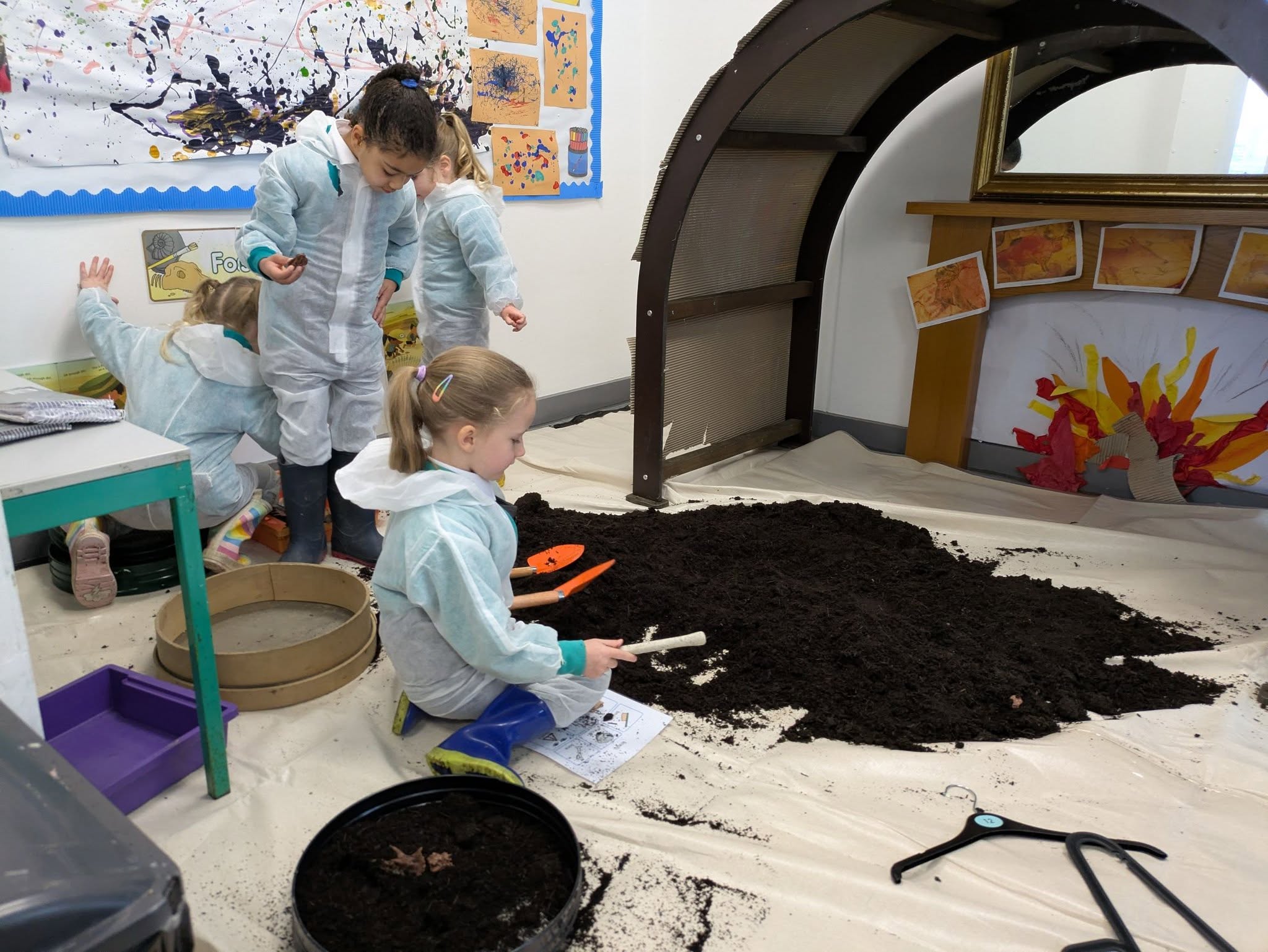 Students in overalls with shovels, digging in soil