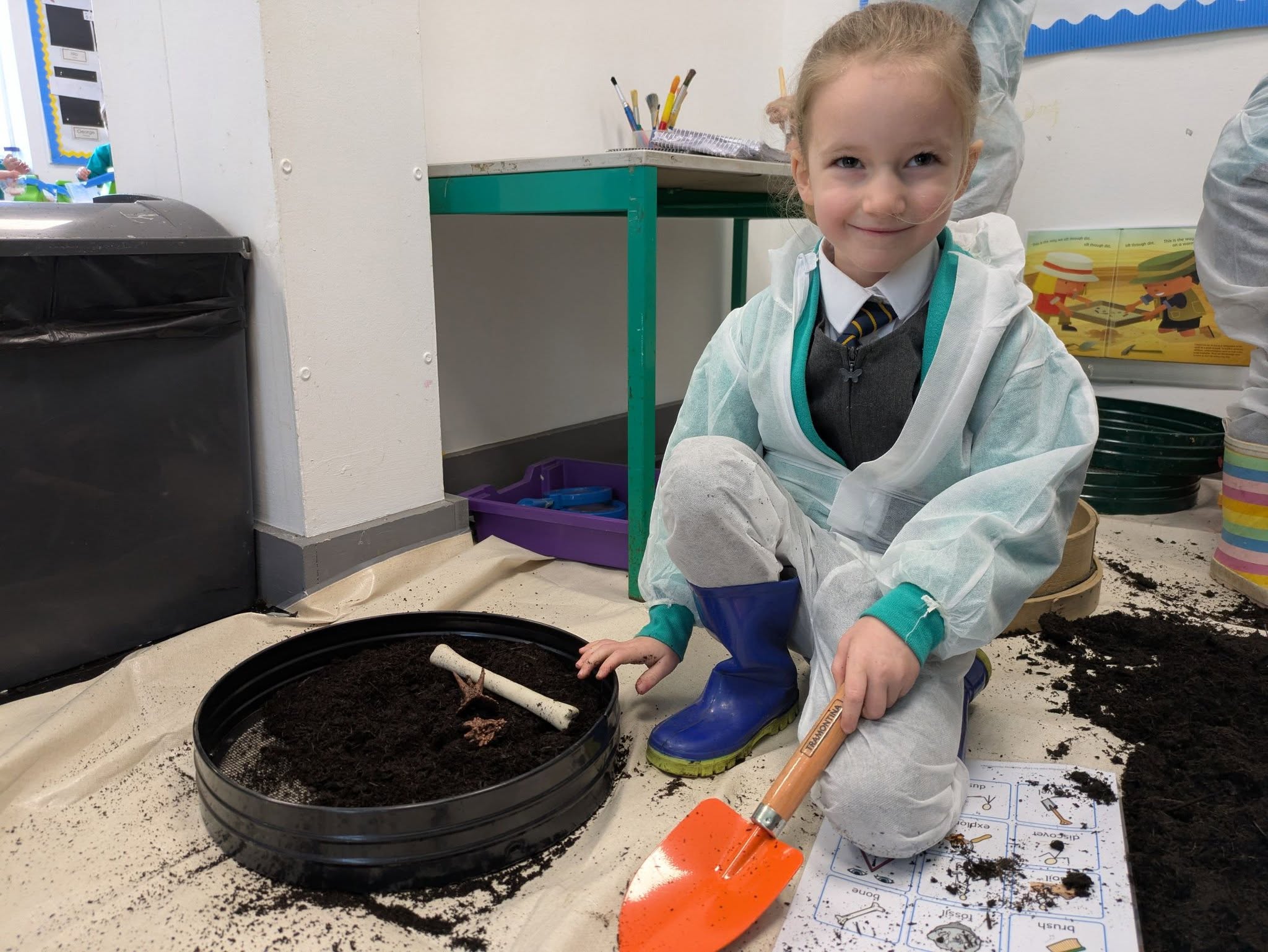 Students in overalls with shovels, digging in soil