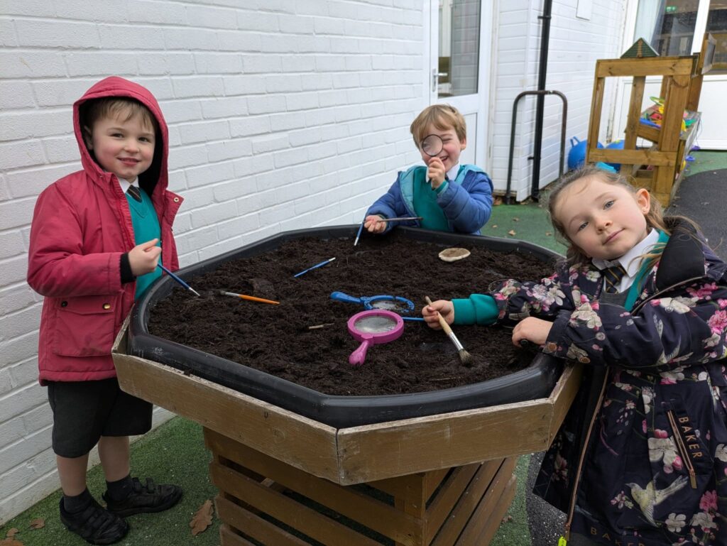 3 students around a tray of soil