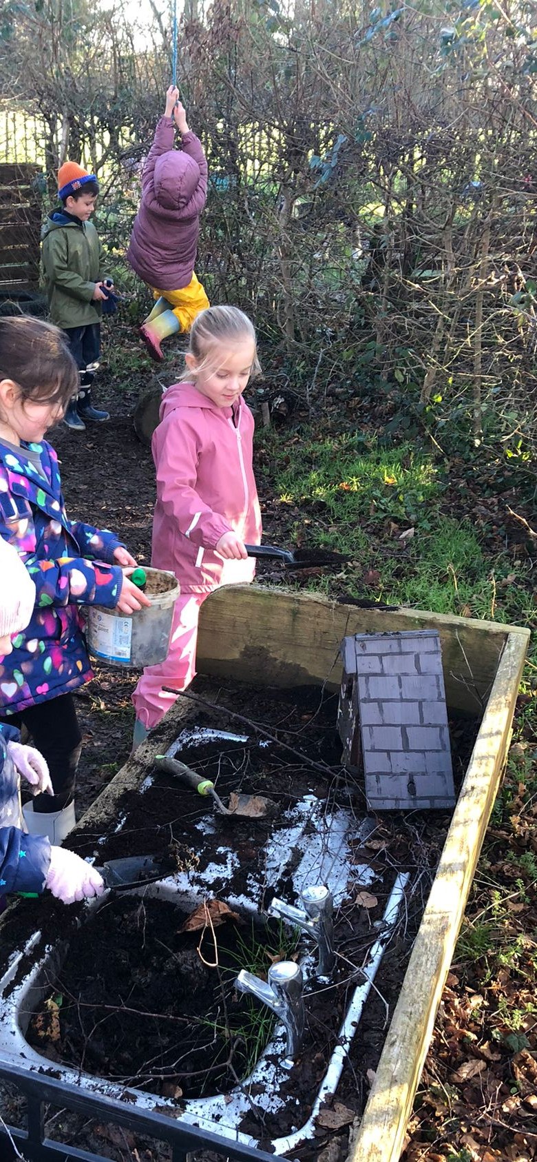 Students in a dirt patch with shovels