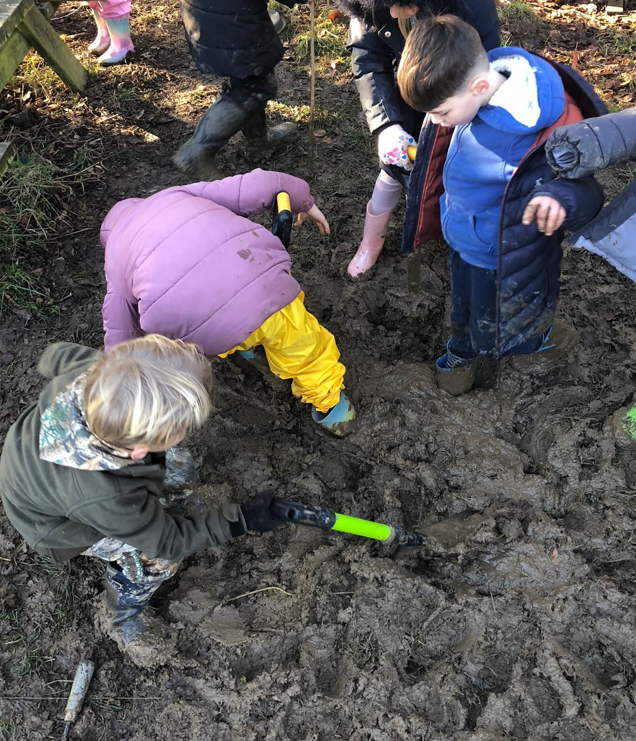 3 students playing in mud