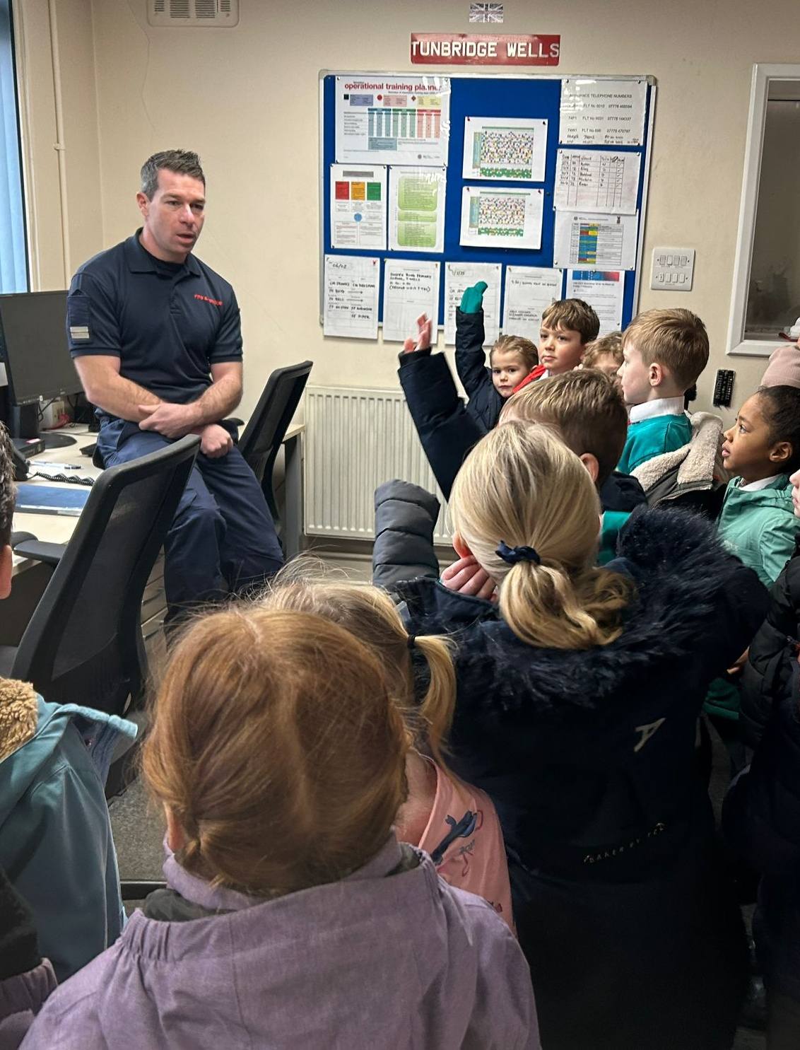 A group of students listening to a firefighter talking