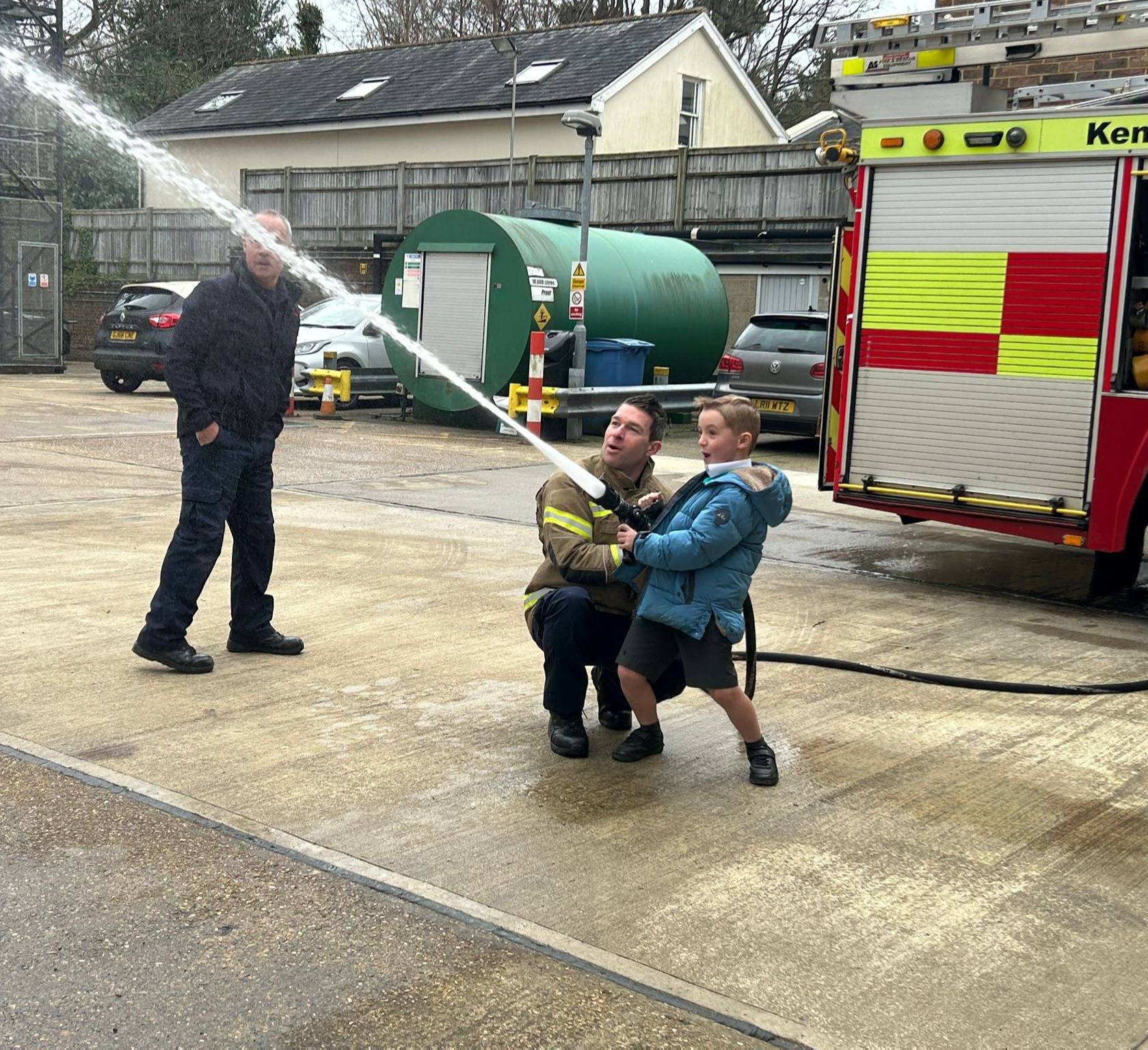 A student using a fire hose with a firefighter