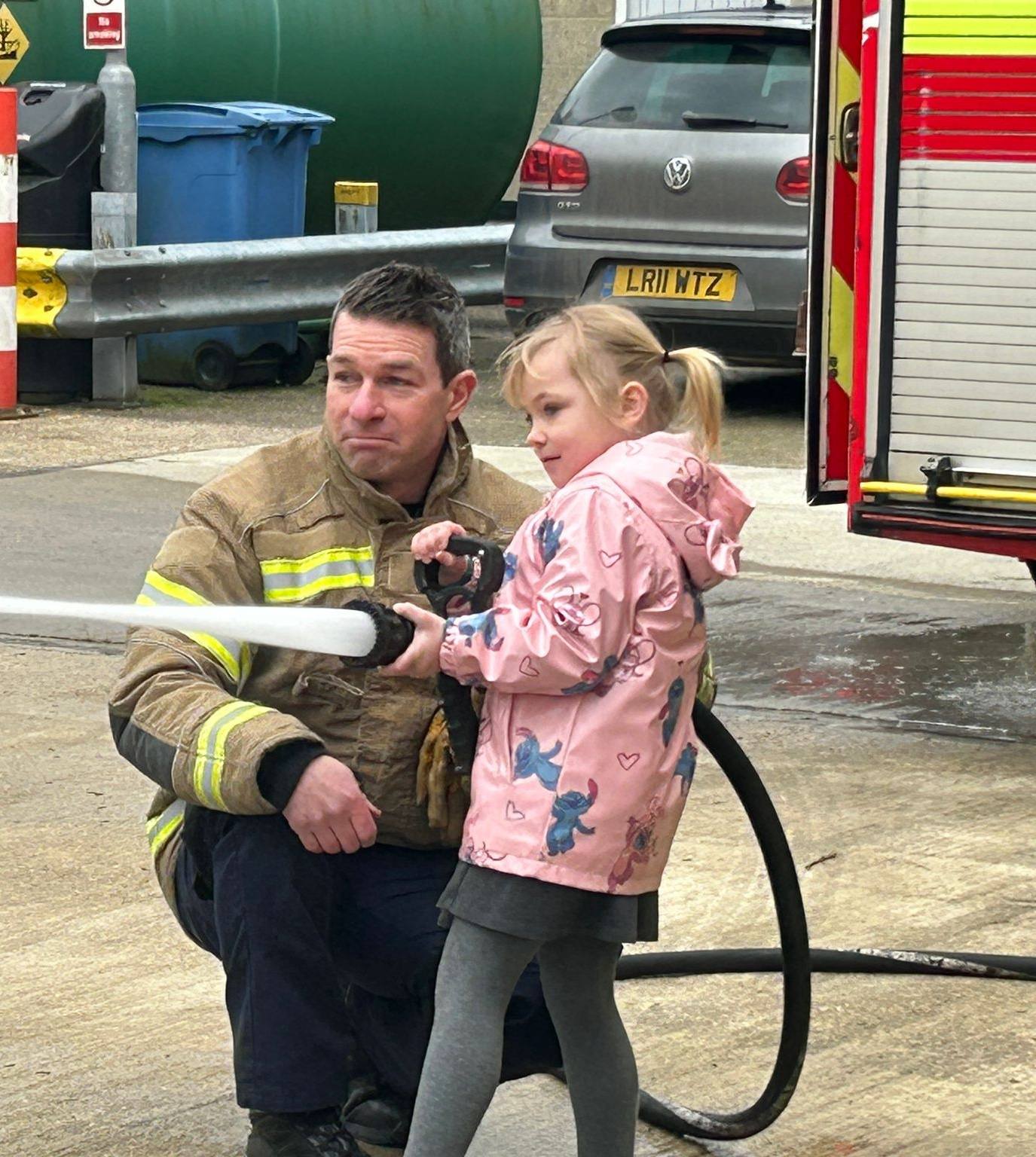 A student using a fire hose with a firefighter