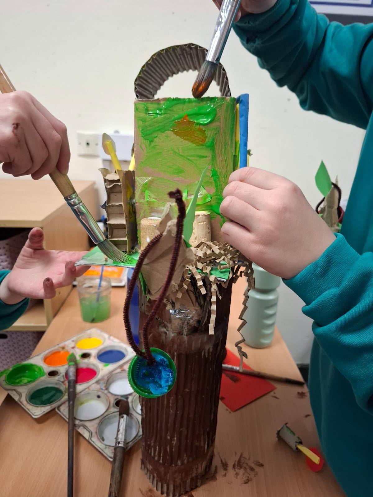 Students at a table, painting their projects