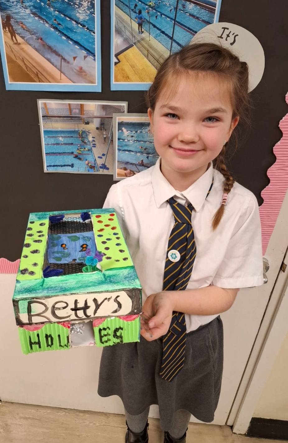 A student smiling, holding up their project