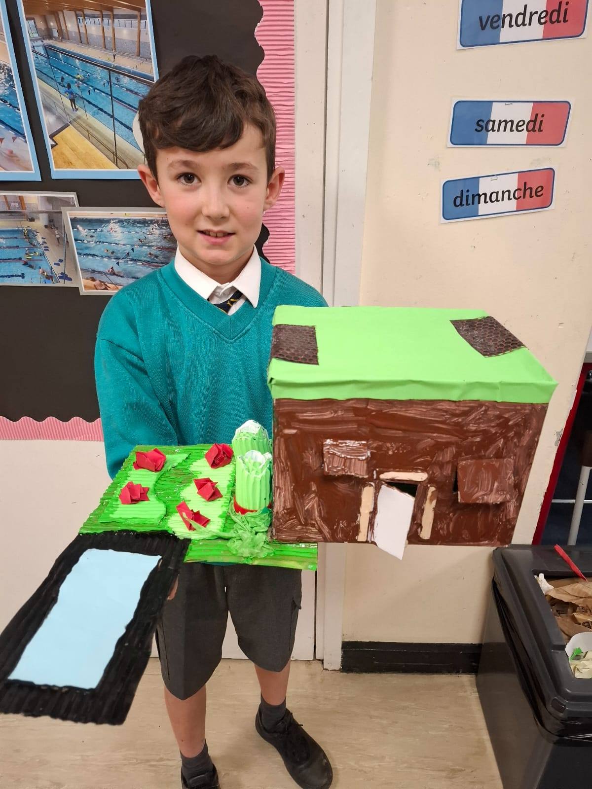 A student smiling, holding up their project
