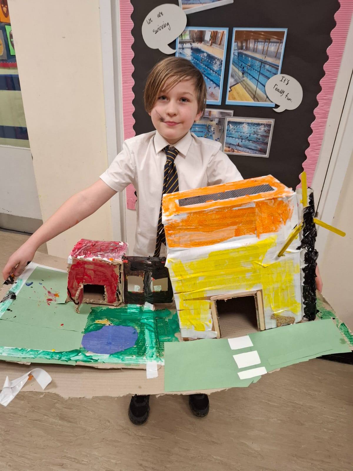 A student smiling, holding up their project