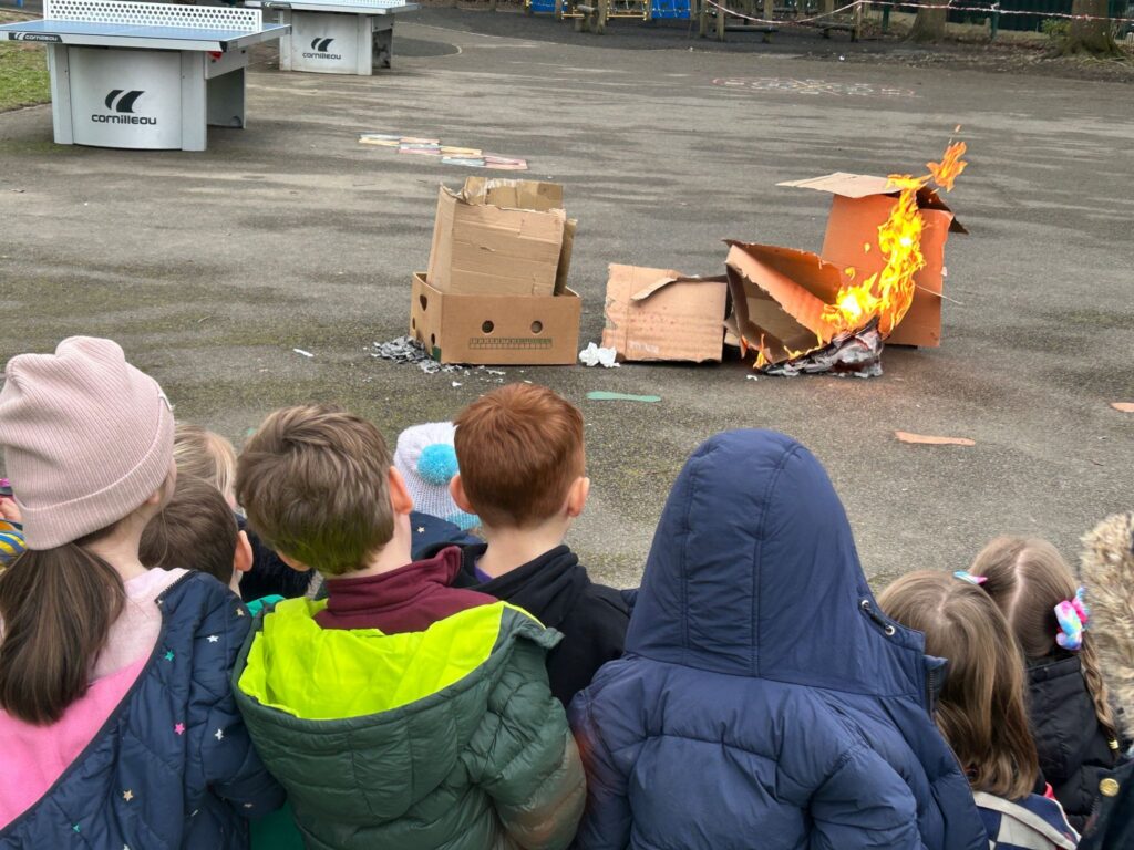 Students watching cardboard boxes on fire