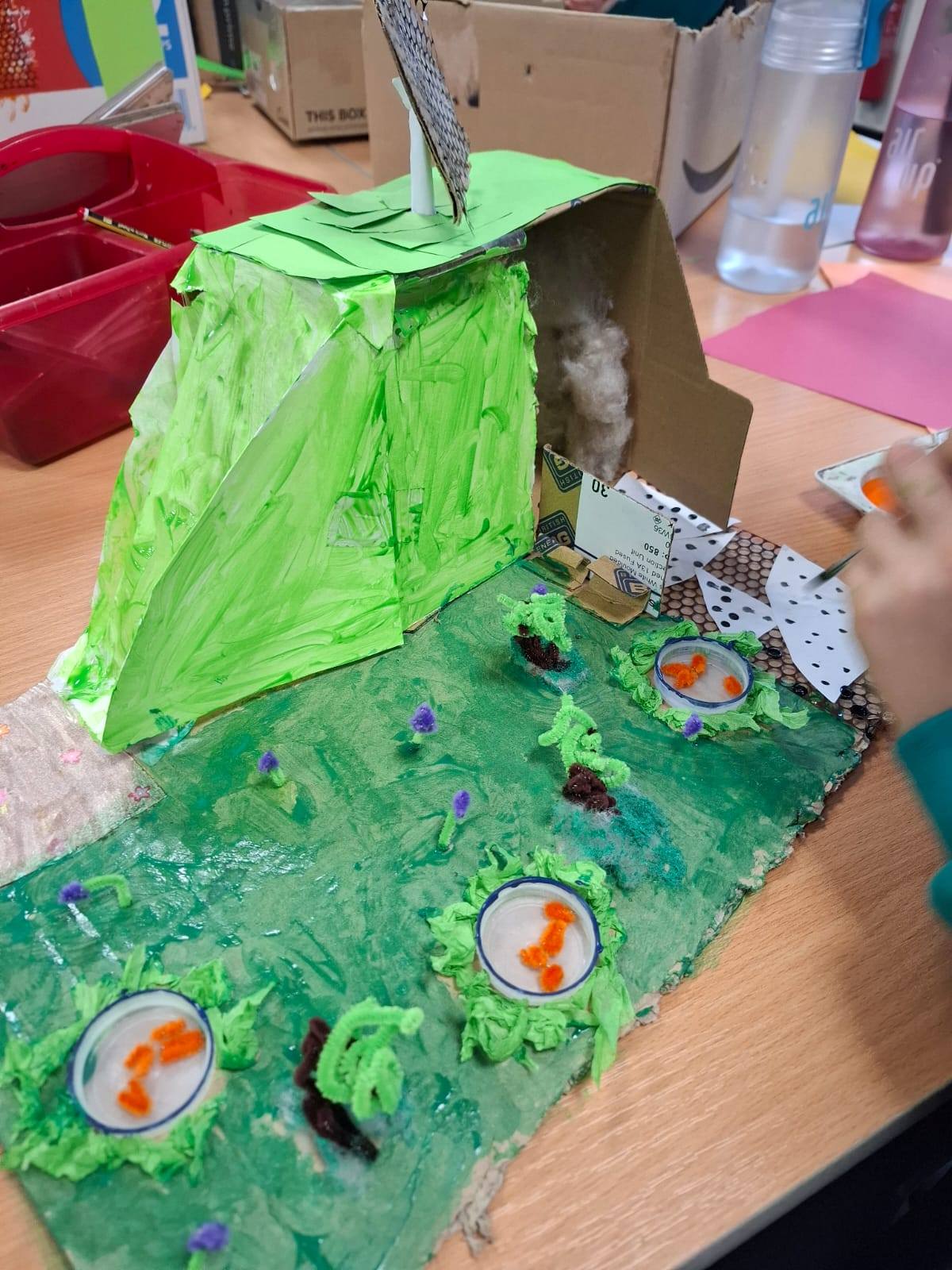A student at a table, painting their project