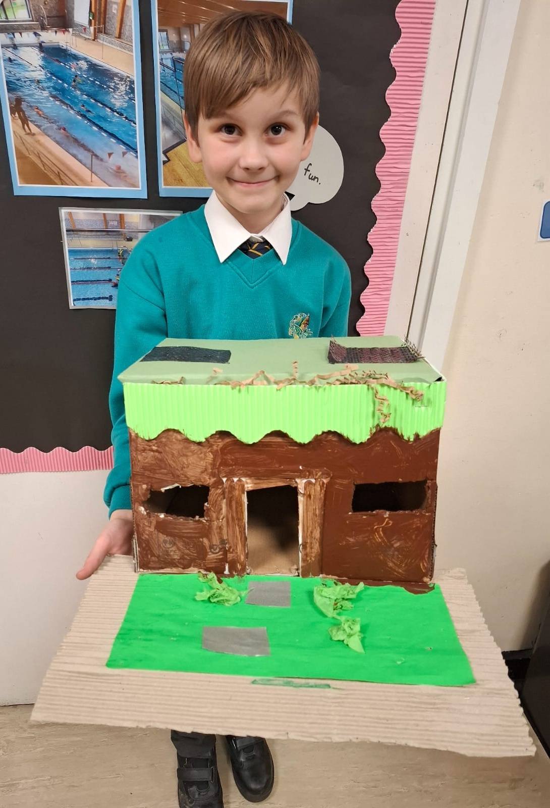 A student smiling, holding up their project