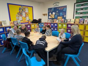 Seven children and three adults read a book in a classroom setting