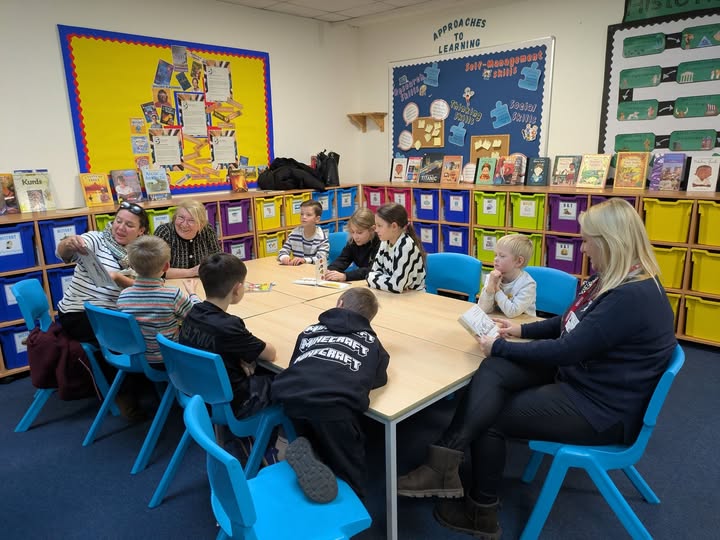 Seven children and three adults read a book in a classroom setting