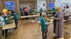 Children and adults making Christmas Wreaths in a school hall setting